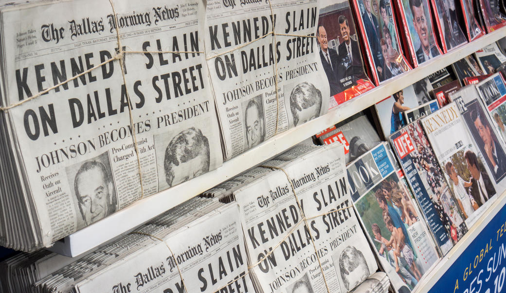 Newspapers with headline reading "Kennedy slain on Dallas street"