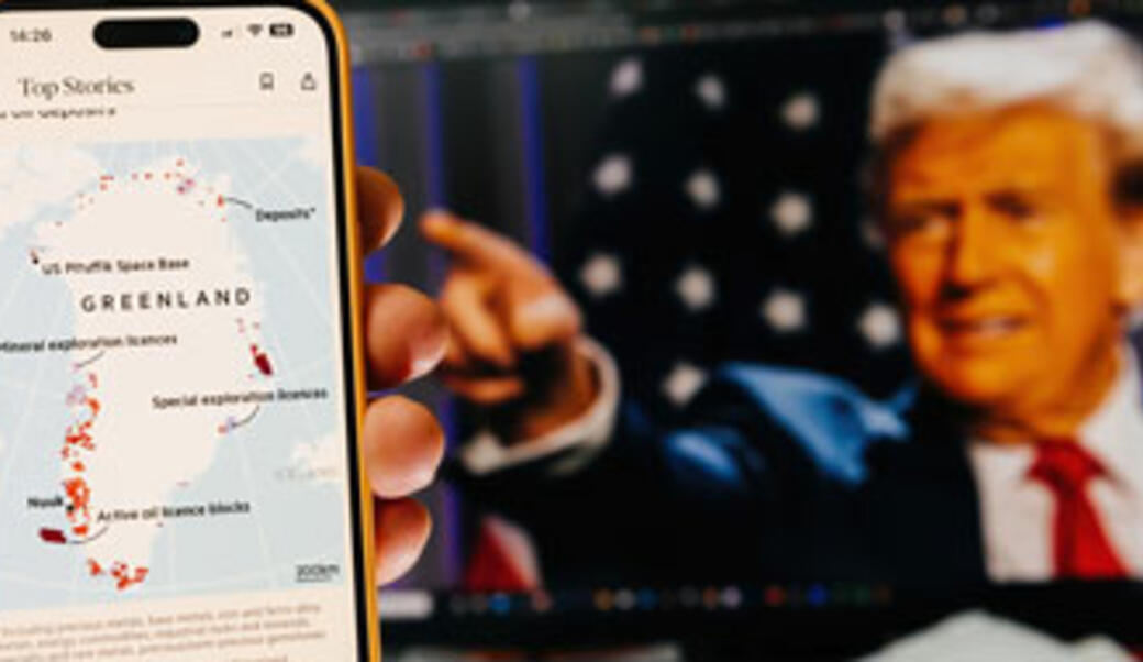 image of hand holding cellphone showing map of Greenland with Trump in the background